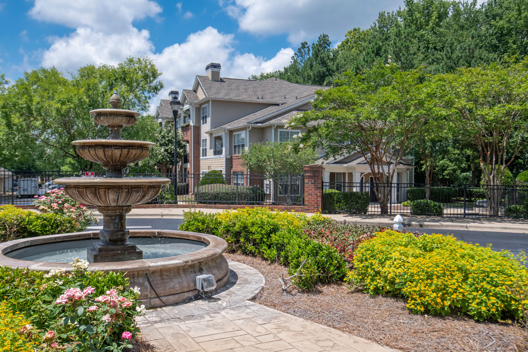 water fountain in front of multifamily building with trees